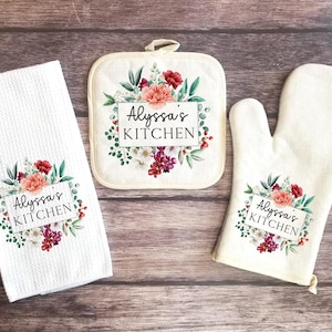 May include: A set of three kitchen items with a floral design and the text "Alyssa's Kitchen". The set includes a potholder, a tea towel, and an oven mitt.