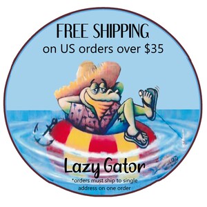 May include: A round, blue graphic featuring a cartoon alligator relaxing in a pool with a life preserver. The alligator wears a straw hat and a Hawaiian shirt. Text reads "FREE SHIPPING on US orders over $35" and "Lazy Gator."