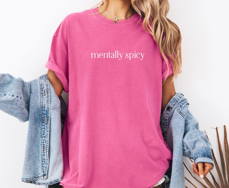 May include: A pink t-shirt with the text "mentally spicy" printed in white on the front.