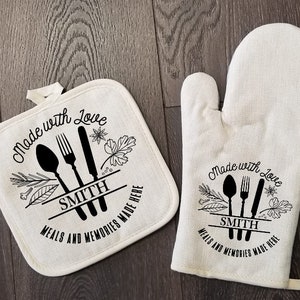 May include: A set of two white cotton pot holders with black text and images. The pot holders feature a spoon, fork, and knife with the text "Made with Love" and "Meals and Memories Made Here". The text "Smith" is also included on the pot holders.