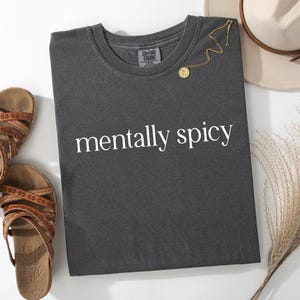 May include: A dark grey t-shirt with the text "mentally spicy" printed in white on the front.