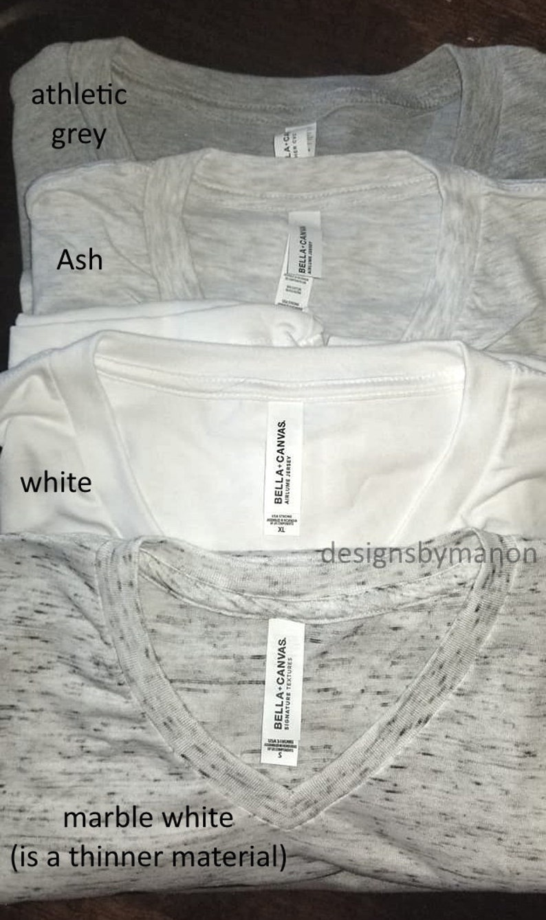 May include: Four different Bella + Canvas t-shirts in various colors: athletic grey, ash, white, and marble white. The marble white t-shirt is labeled as a thinner material.