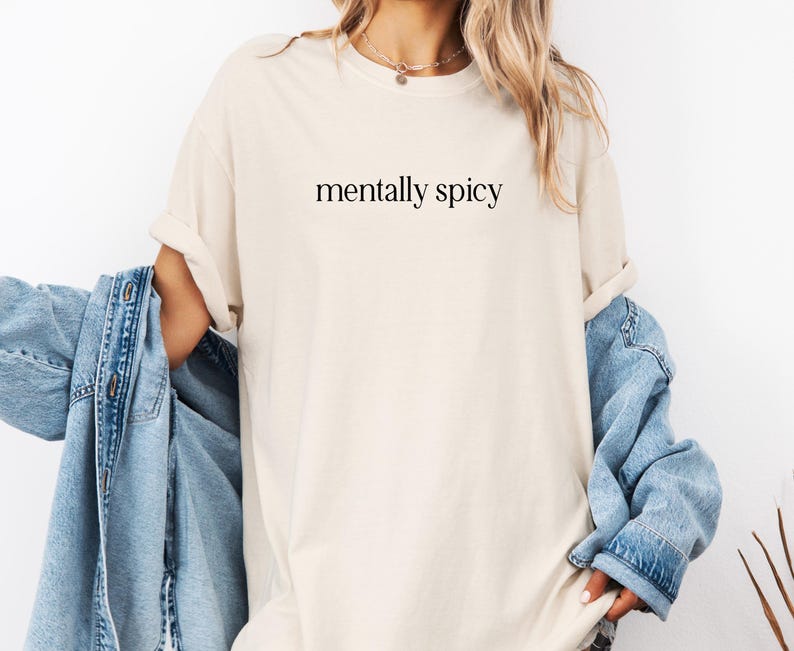 May include: A beige t-shirt with the text "mentally spicy" printed in black.
