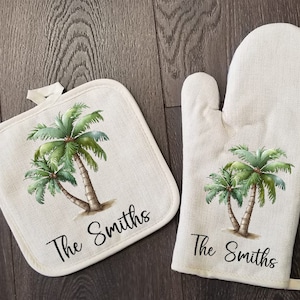 May include: A set of two white cotton pot holders with a palm tree design and the text "The Smiths".