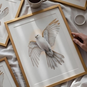 Puede incluir: Impresiones artísticas enmarcadas que muestran una paloma blanca con detalles dorados en sus alas. La paloma está representada en pleno vuelo sobre un fondo blanco. Los marcos son dorados y la obra se exhibe sobre una superficie blanca.