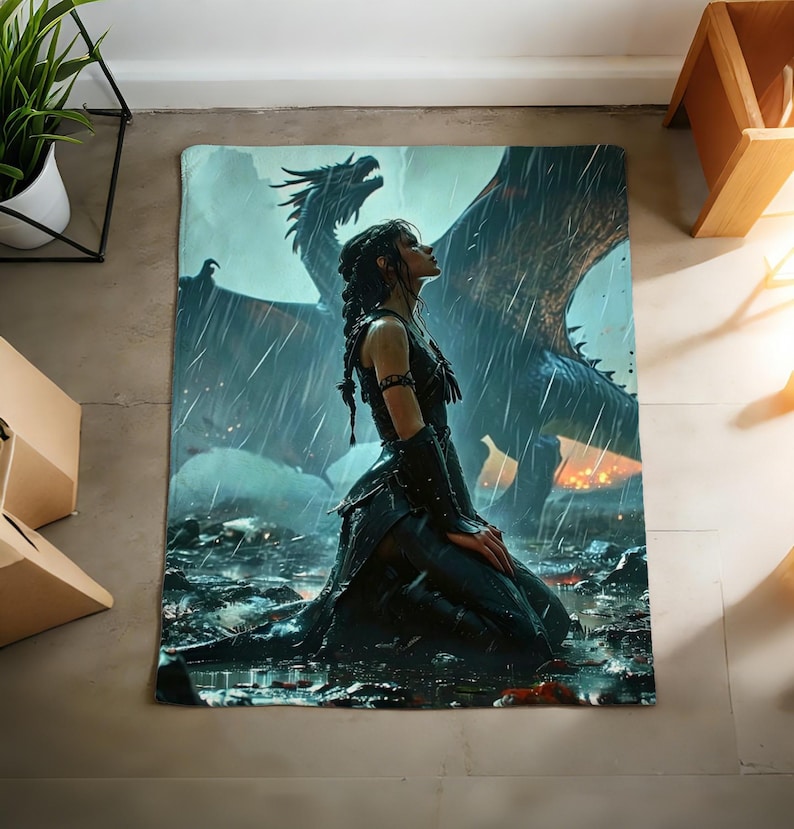 K&ouml;nnte beinhalten: Eine Fantasy-Decke mit einer knienden Frau im Regen und einem Drachen im Hintergrund. Die Kunst verwendet Blau-, Grau- und Schwarzt&ouml;ne, wodurch eine dramatische Szene entsteht. Die Decke ist rechteckig und f&uuml;r Betten oder Sofas geeignet.