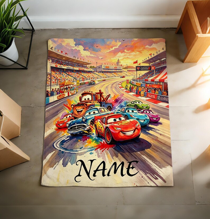 Pu&ograve; includere: Una coperta rettangolare con una colorata illustrazione di auto da corsa animate su una pista con uno stadio sullo sfondo. Il design include un'auto rossa con il numero 95, un'auto blu e un carro attrezzi marrone. La parola NAME &egrave; stampata in nero.
