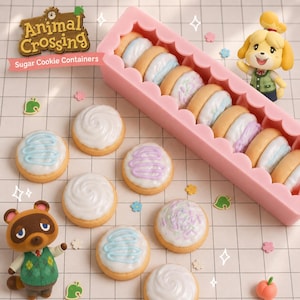 May include: A pink scalloped container filled with round sugar cookies, accompanied by Animal Crossing character figurines of Isabelle and Tom Nook. The cookies feature white icing with blue or purple drizzle and sprinkles, alongside small leaf-shaped icons.