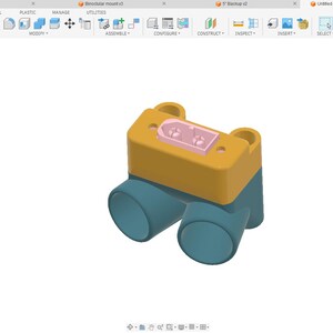 Op de afbeelding: 3D-model van een mechanisch onderdeel. Het ontwerp heeft een gele rechthoekige bovenkant met twee roze rechthoeken en twee blauwe cilindrische buizen. Het onderdeel staat tegen een witte achtergrond.