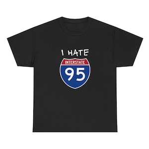 May include: Black t-shirt with the text "I HATE INTERSTATE 95" above a graphic of the Interstate 95 highway sign. The sign is blue, red, and white. The shirt is a crew neck.