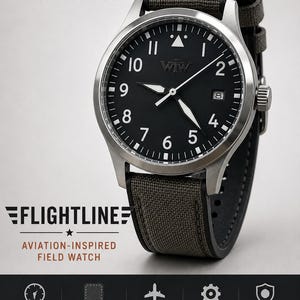 K&ouml;nnte beinhalten: Eine Feldarmbanduhr aus Edelstahl mit schwarzem Zifferblatt, wei&szlig;en arabischen Ziffern und einem Datumsfenster auf der Drei-Uhr-Position. Die Uhr verf&uuml;gt &uuml;ber ein graues Hybridarmband aus Cordura-Stoff und Silikon mit sichtbaren N&auml;hten und Krone.