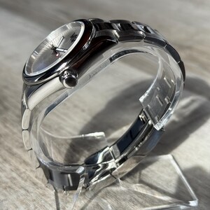 Puede incluir: Un reloj de pulsera anal&oacute;gico plateado con caja met&aacute;lica redonda y brazalete de eslabones a juego. La esfera tiene una textura plateada con manecillas plateadas y un peque&ntilde;o detalle rojo en el segundero, protegido por un cristal transparente.