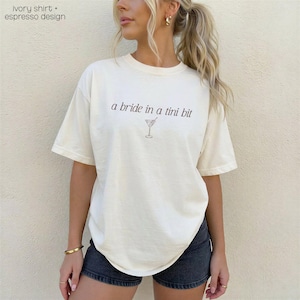 Bride in a Tini Bit Bride Shirt Tini Bit Engaged Bachelorette Party Custom Bachelorette Shirt for Bride to Be, Bride Sweatshirt Future Mrs Shirt, Mrs Personalized Bride Shirt | Bride Clothes Future Mrs Engaged Custom Mrs Shirt Custom Wife Shirt. Bridal Sweatshirt Bachelorette Shirts. Custom Bachelorette Shirt Bachelorette Party Shirts. Custom Bridesmaid Shirts This is a personalized getting ready outfit for wedding day. Perfect for a wedding newly engaged gift. It is a comfort colors 1717 shirt.