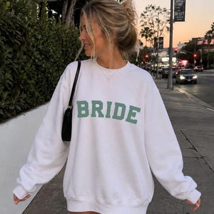 Bride Crewneck Bridal Sweatshirt Engaged gift for her custom mrs shirt announce engagement personalized wifey get married custom engaged shirt bride getting ready outfit future mrs engaged just engaged gift just married shirt bride hoodie mrs hoodie wifey sweatshirt bride mrs sweatshirt. bride clothes, wedding newly engaged gift. This is a custom bride crewneck bridal sweatshirt. It's a gildan 18000 crewneck sweatshirt.