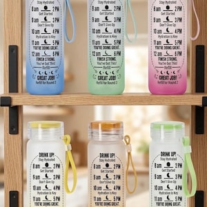 May include: Six frosted plastic water bottles with matching colored lids and carrying straps. Each bottle features a printed hourly hydration schedule with text including DRINK UP!, Stay Hydrated, Get Started, Don't Give Up, Hydration is Key, YOU'RE DOING GREAT, FINISH STRONG, You've Got This!, Refill, and GREAT JOB!