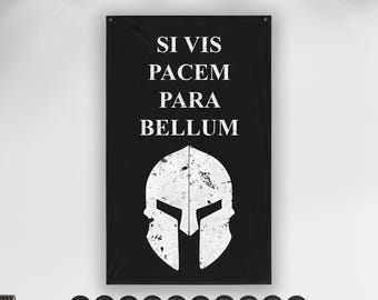 Peut inclure: Une bannière murale rectangulaire noire avec le texte blanc SI VIS PACEM PARA BELLUM centré au-dessus d'un grand graphique blanc vieilli représentant un casque spartiate. La bannière comporte des œillets métalliques aux coins supérieurs.