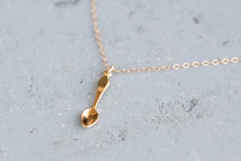 gold chain necklace with a small gold spoon pendant.