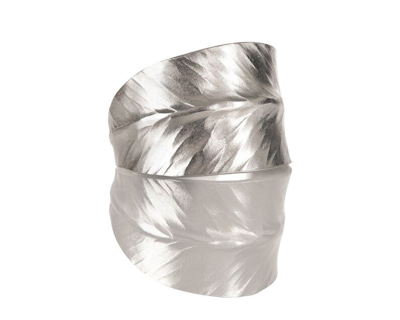 May include: A silver leaf-shaped ring with a textured surface.