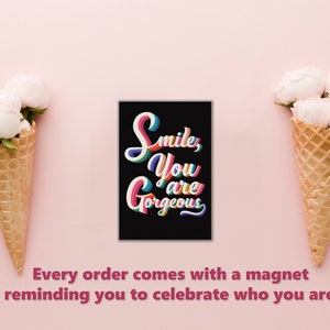 Puede incluir: Un im&aacute;n negro con el texto "Smile, You are Gorgeous" en letras estilizadas de colores. El im&aacute;n est&aacute; rodeado de dos conos de waffle llenos de flores blancas sobre un fondo rosa.