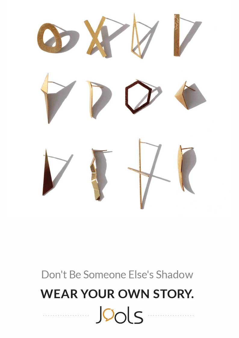 May include: A collection of gold and brown geometric earrings, including a circle, an X, a triangle, a rectangle, a curved shape, a hexagon, a triangle, a curved shape, a triangle, a wavy shape, a cross, and a curved shape. The text "Don't Be Someone Else's Shadow" and "WEAR YOUR OWN STORY." is displayed below the earrings. The word "Jools" is displayed below the text in a stylized font with a speech bubble.