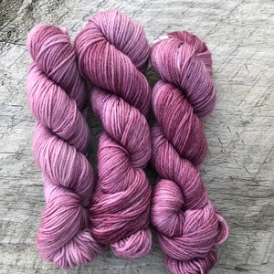 Pode incluir: Tr&ecirc;s novelos de fio em tons de rosa e roxo. O fio &eacute; macio e felpudo, e seria perfeito para tricotar ou fazer croch&ecirc;.