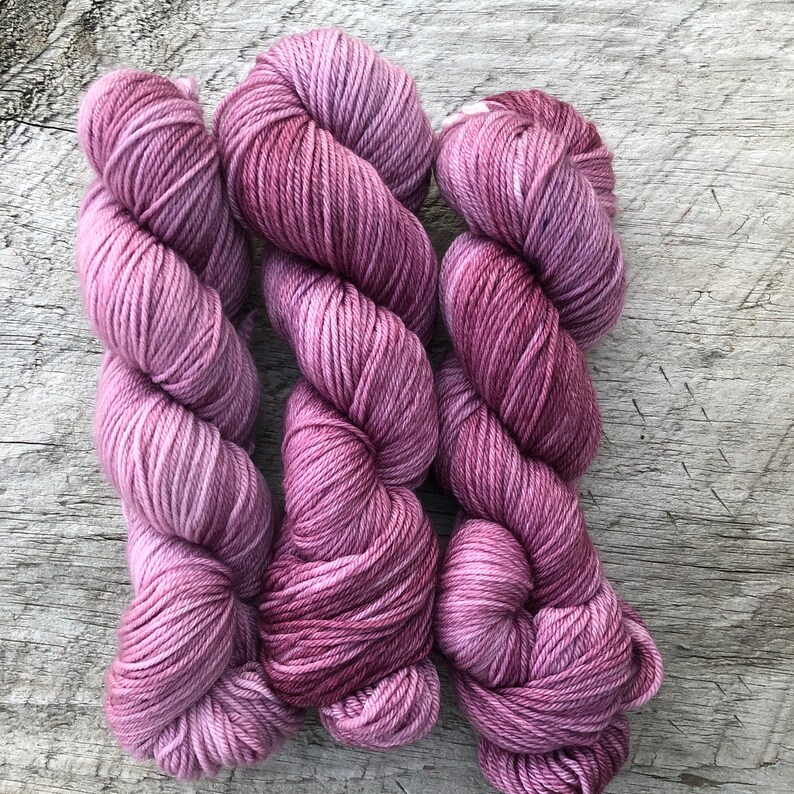 Pode incluir: Tr&ecirc;s novelos de fio em tons de rosa e roxo. O fio &eacute; macio e felpudo, e seria perfeito para tricotar ou fazer croch&ecirc;.