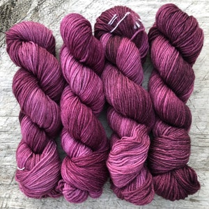Pode incluir: Tr&ecirc;s novelos de fio roxo escuro com um efeito degrad&ecirc; sutil. O fio &eacute; macio e felpudo, perfeito para tricotar ou fazer croch&ecirc;.