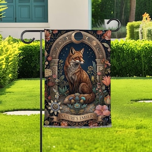 May include: A garden flag featuring a detailed illustration of a fox with brown fur, set against a dark blue background with floral and celestial elements. The text "NATURE'S EMBERS" is displayed on a banner at the bottom.