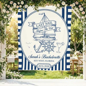 May include: A rectangular cream-colored fabric banner with dark blue vertical stripes on the sides. The center features a dark blue nautical design with a sailboat, anchor, ship wheel, and cocktail glass, with the text "LAST SAIL Before The Veil", "Sarah's Bachelorette", "KEY WEST, FLORIDA", and "AUG 2026".