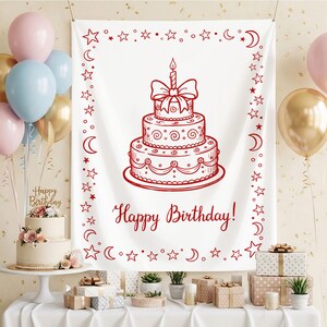 May include: A white rectangular fabric backdrop featuring a red line-art illustration of a three-tiered birthday cake topped with a single candle and a bow. The border is decorated with red stars and moons, with the text Happy Birthday! below.