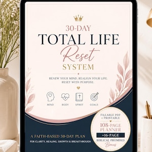 May include: A digital tablet shows a planner titled "30-Day Total Life Reset System." The design features a navy blue and blush pink colour scheme with floral accents. The planner includes sections for mind, body, spirit, and goals, with a bonus of biblical promises.