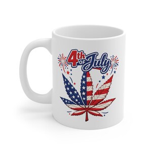 Op de afbeelding: Witte keramische mok met een cannabisbladontwerp in de kleuren van de Amerikaanse vlag. Het blad is verdeeld in secties met blauwe sterren en rood-witte strepen. De woorden "4th of July" staan boven het blad.