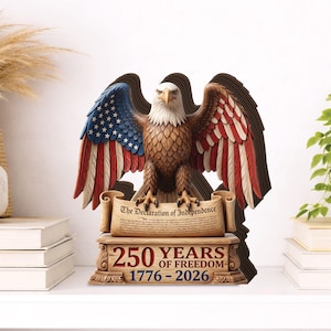 May include: A wooden sculpture of a bald eagle with outstretched wings, featuring the American flag design on the wings. The sculpture includes the text "The Declaration of Independence" and "250 YEARS OF FREEDOM 1776-2026".