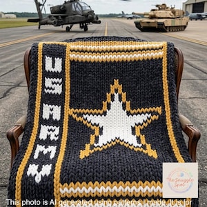 May include: A dark gray knitted blanket with a large white star and gold accents, draped over a chair. The blanket features the text "US ARMY" in white. The background shows military vehicles, including a helicopter and a tank. The text in the image says: "This photo is AI generated using patterns I made."