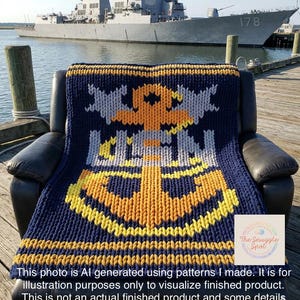 Pode incluir: Cobertor de malha azul marinho com um grande desenho de âncora em amarelo e laranja. O cobertor está sobre uma poltrona de couro preta, com um navio de guerra ao fundo. O cobertor tem uma aparência texturizada.