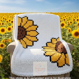 May include: A white, chunky-knit blanket draped over a chair, featuring two large sunflower designs in yellow, brown, and black. The blanket is set against a backdrop of a sunflower field under a blue sky. The text on the blanket says "The Snuggle Spot".