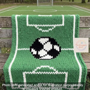 Pode incluir: Um cobertor de malha verde e branco com um design de campo de futebol, apresentando uma bola de futebol preta e branca no centro. O cobertor é exibido em um banco de madeira com um campo de futebol ao fundo. O texto diz: Foto gerada por IA.