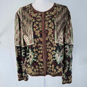 Puede incluir: Chaqueta totalmente con lentejuelas con cuello redondo y mangas largas. La chaqueta presenta una base negra con estampados florales y geom&eacute;tricos en dorado, rojo y verde. Las mangas y la parte superior del cuerpo tienen rayas verticales en tonos marrones, verdes y dorados.