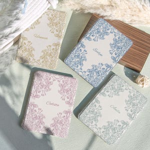 May include: A white ceramic mug with a black handle and the text "But First, Coffee" in a black, handwritten-style font. The mug is on a white surface.