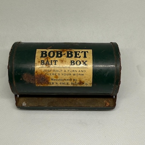 May include: Vintage green metal BOB-BET BAIT BOX with a rectangular label. The label reads "BOB-BET BAIT BOX" and "JUST HALF A TURN AND THERE'S YOUR WORM." Manufactured by LER S. COLE, Beaver, Wis. The bait box has a metal handle.