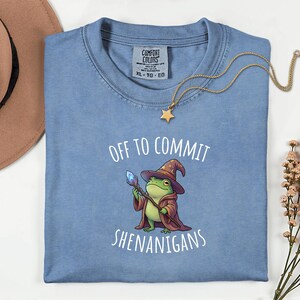 May include: A white ceramic mug with a black handle and the text "But First, Coffee" in a handwritten style. The mug is on a white surface. The mug is approximately 4 inches tall.