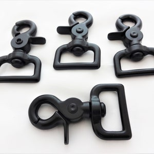 Puede incluir: Cuatro mosquetones giratorios de metal negro. Los mosquetones tienen un bucle rectangular y una puerta de cierre con resorte.