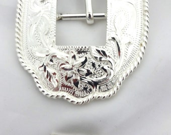 May include: Silver-toned belt buckle with a floral design and a square buckle. The buckle is attached to a matching silver-toned strap with a floral design.
