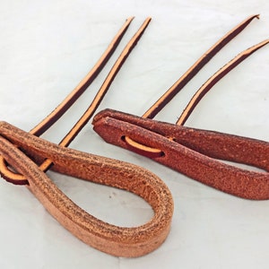 May include: Two brown leather loops with long leather straps. The loops are about 3 inches long and 1 inch wide. The straps are about 12 inches long.
