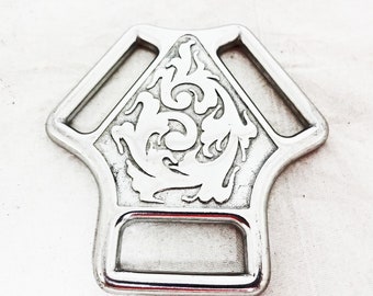 May include: Silver-toned metal horse bit with a decorative floral design. The bit has two rings and a center loop.