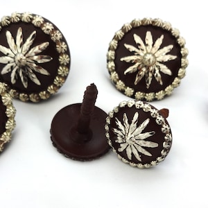 Pode incluir: Cinco tachas decorativas marrons e douradas com um design de estrela. As tachas têm uma parte de trás de parafuso.