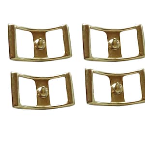Puede incluir: Cuatro hebillas de metal de color dorado con una pieza central puntiaguda. Las hebillas están diseñadas para ser usadas para correas o cinturones.
