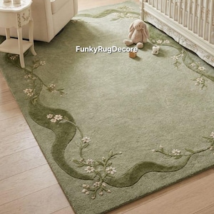 May include: A rectangular sage green area rug featuring a darker green wavy border with embroidered white floral vine patterns. The text FunkyRugDecore is printed in white in the center of the rug, which has a soft, textured pile surface.