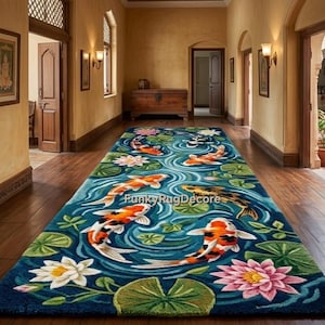 Pode incluir: Um tapete retangular azul com um design de lagoa de carpas koi. O tapete apresenta peixes koi laranja, brancos e pretos nadando entre nenúfares e flores de lótus. O tapete é colocado em um corredor com pisos e paredes de madeira.