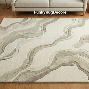 May include: A rectangular area rug with a cream-colored background and flowing, abstract patterns in shades of gray and beige. The rug is placed on a wooden floor, and the text "FunkyRugDecor" is visible on the rug.